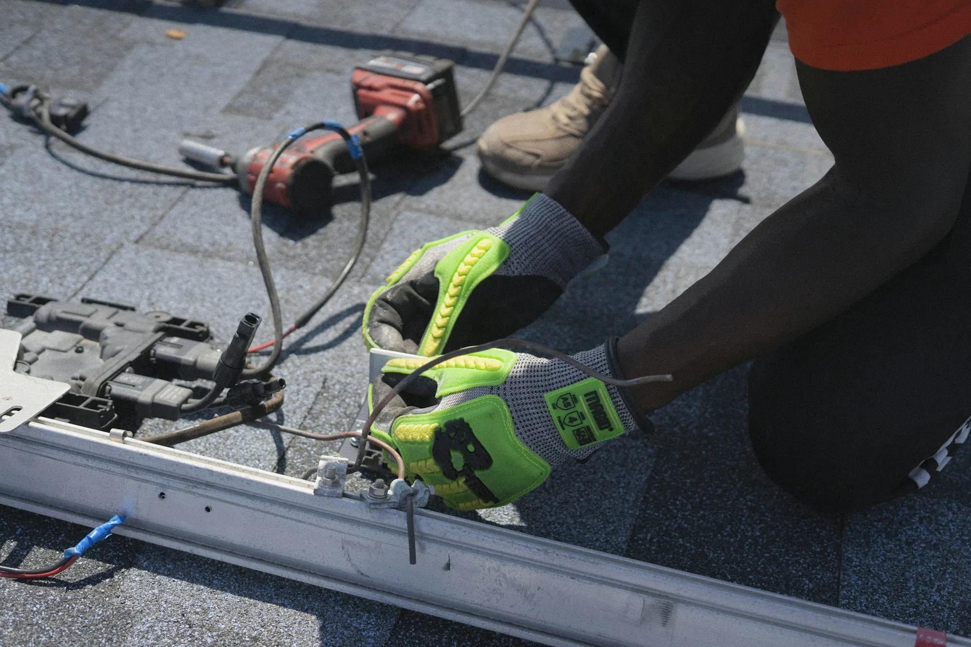 Gloved hands of a roofer fastening metal drip edge on a shingle roof
