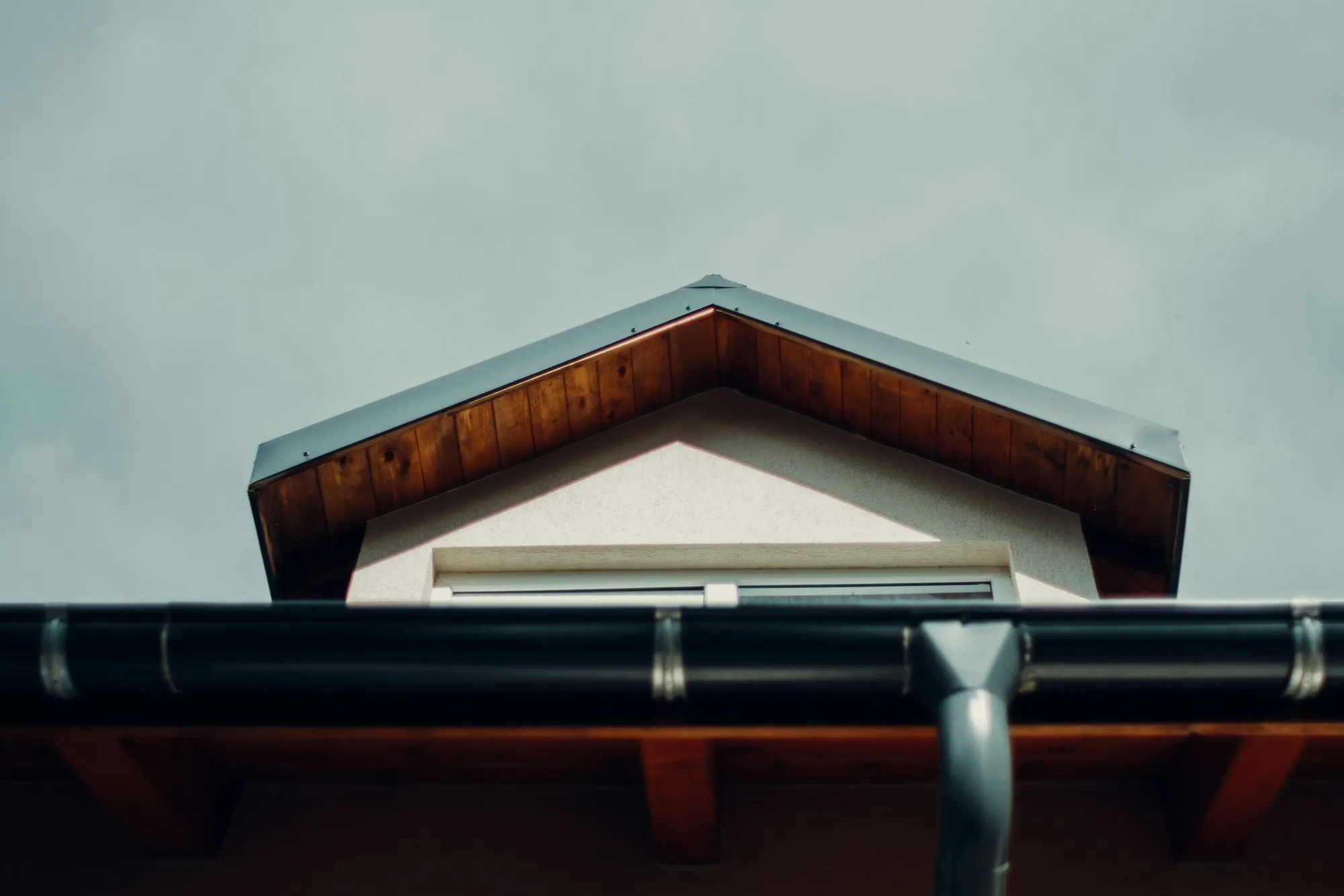 Dark gutter and downspout running beneath a small gable