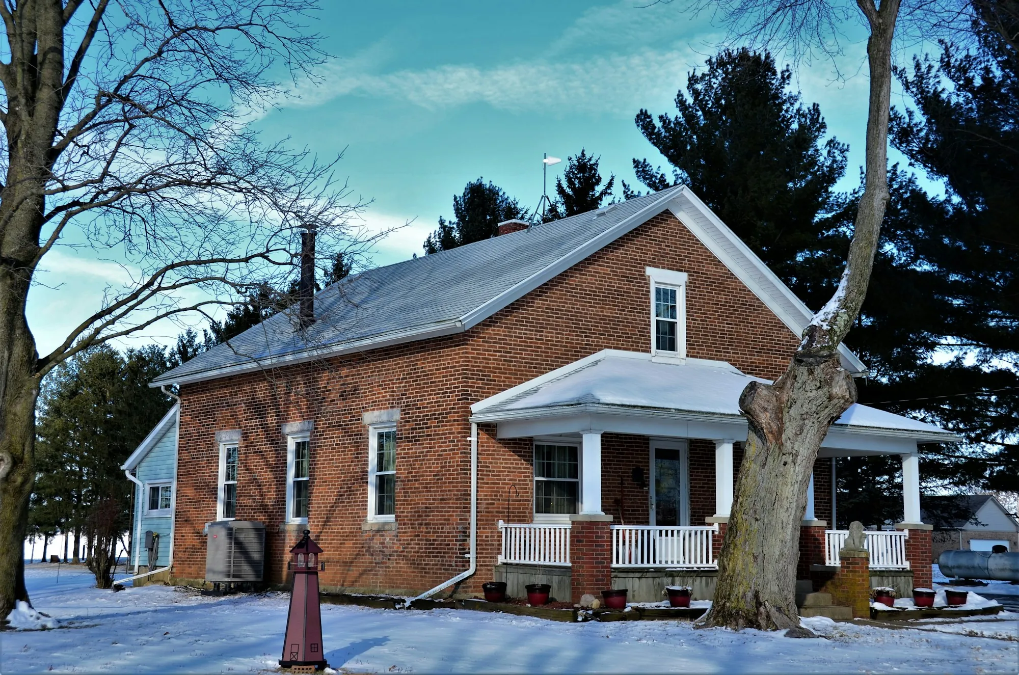 Brick house with a white front porch in light snow