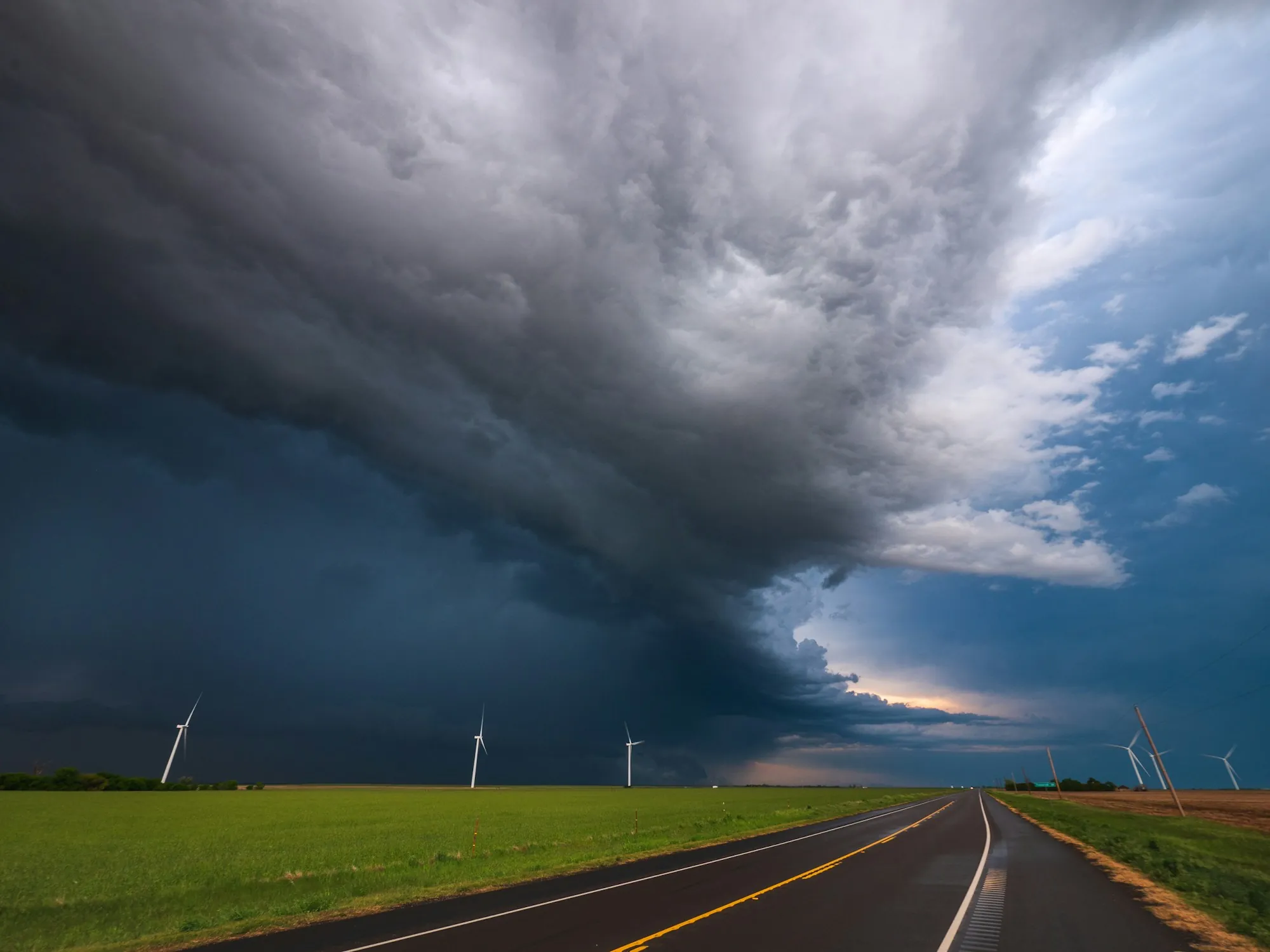 Storm cell over a rural highway and wind turbines